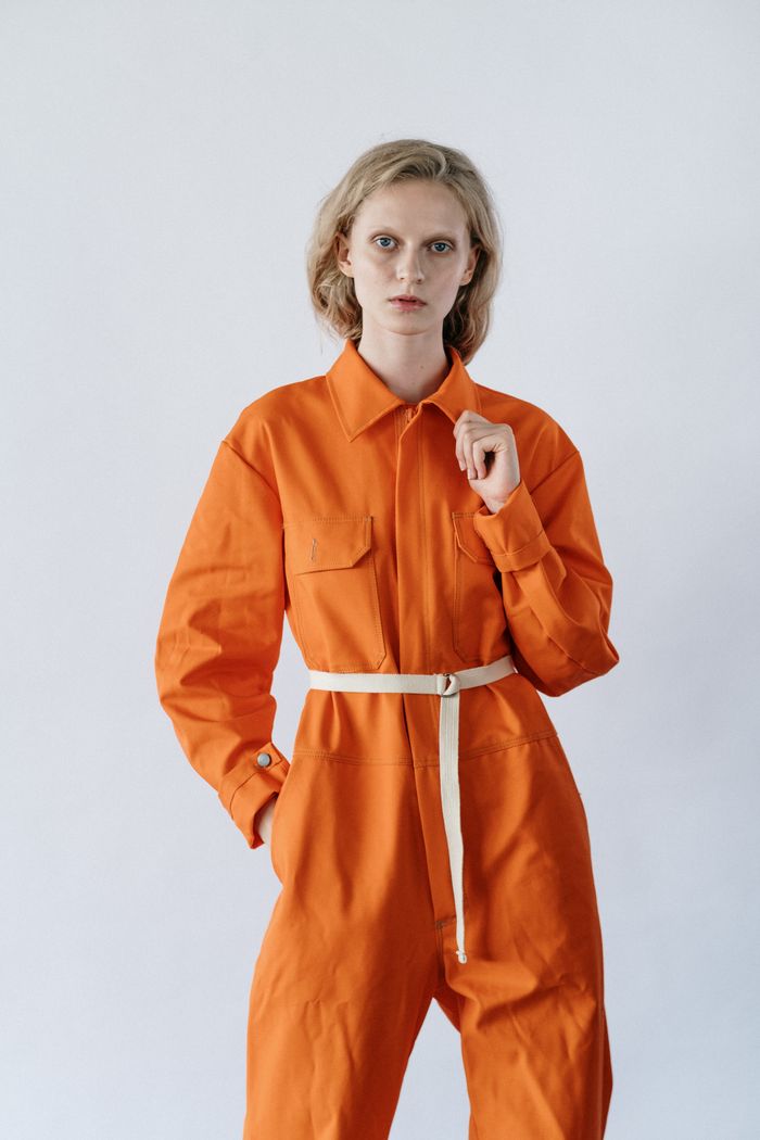 Services-03 Stylish woman posing in orange utility jumpsuit against a plain background.
